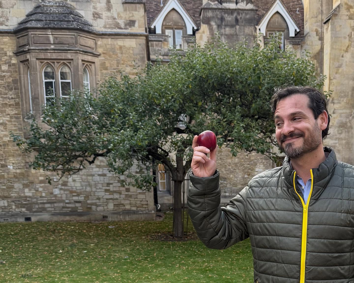 Alberto sostiene una manzana delante del manzano de Newton en Cambridge