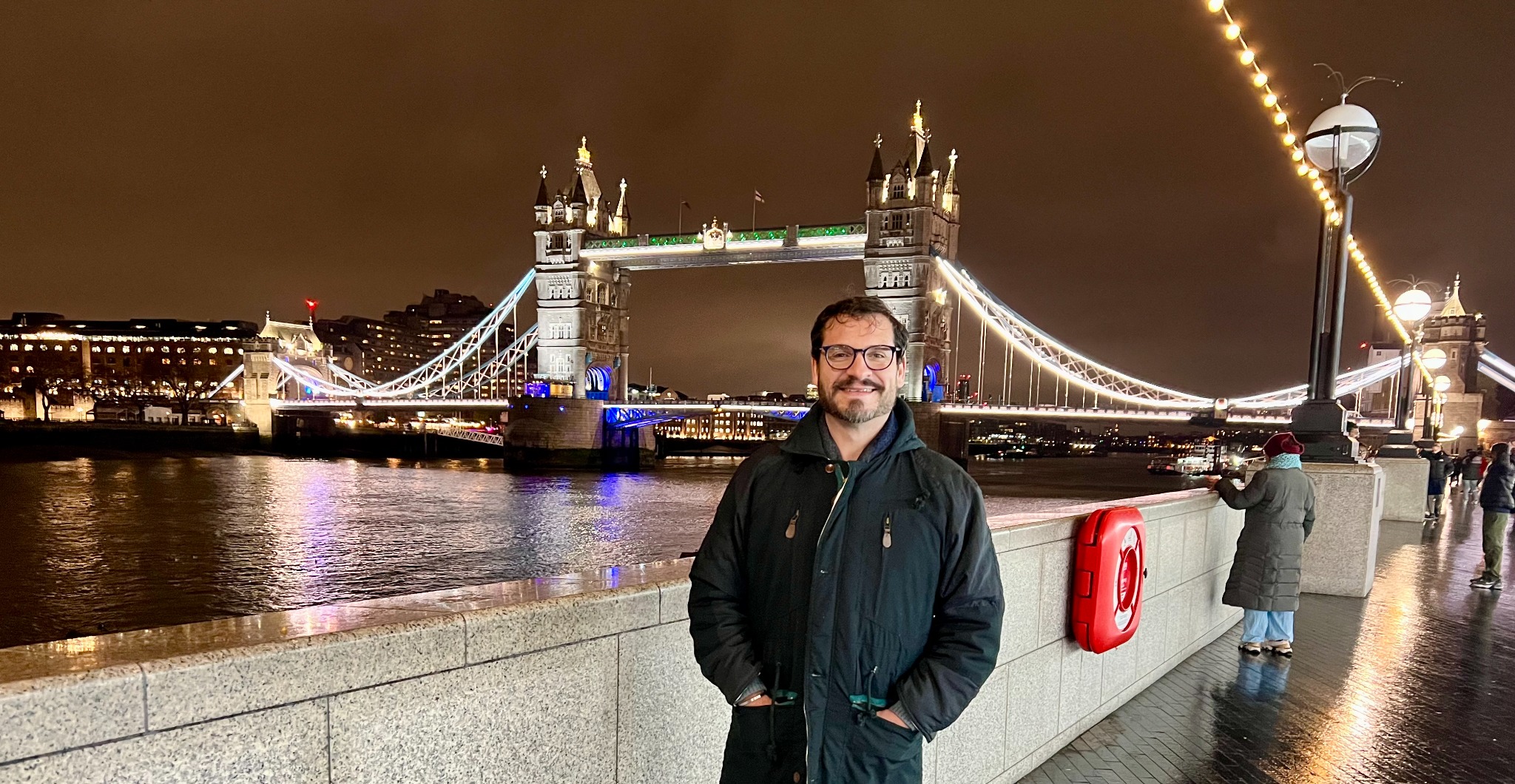 Alberto junto al Támesis con Tower Bridge iluminado por la noche